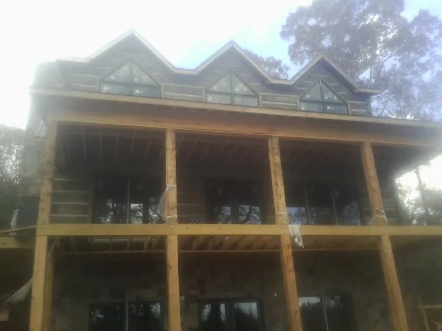 Dormers and porch framing on a large log home under construction — Roof Coating work by our crew in Saddle Brook