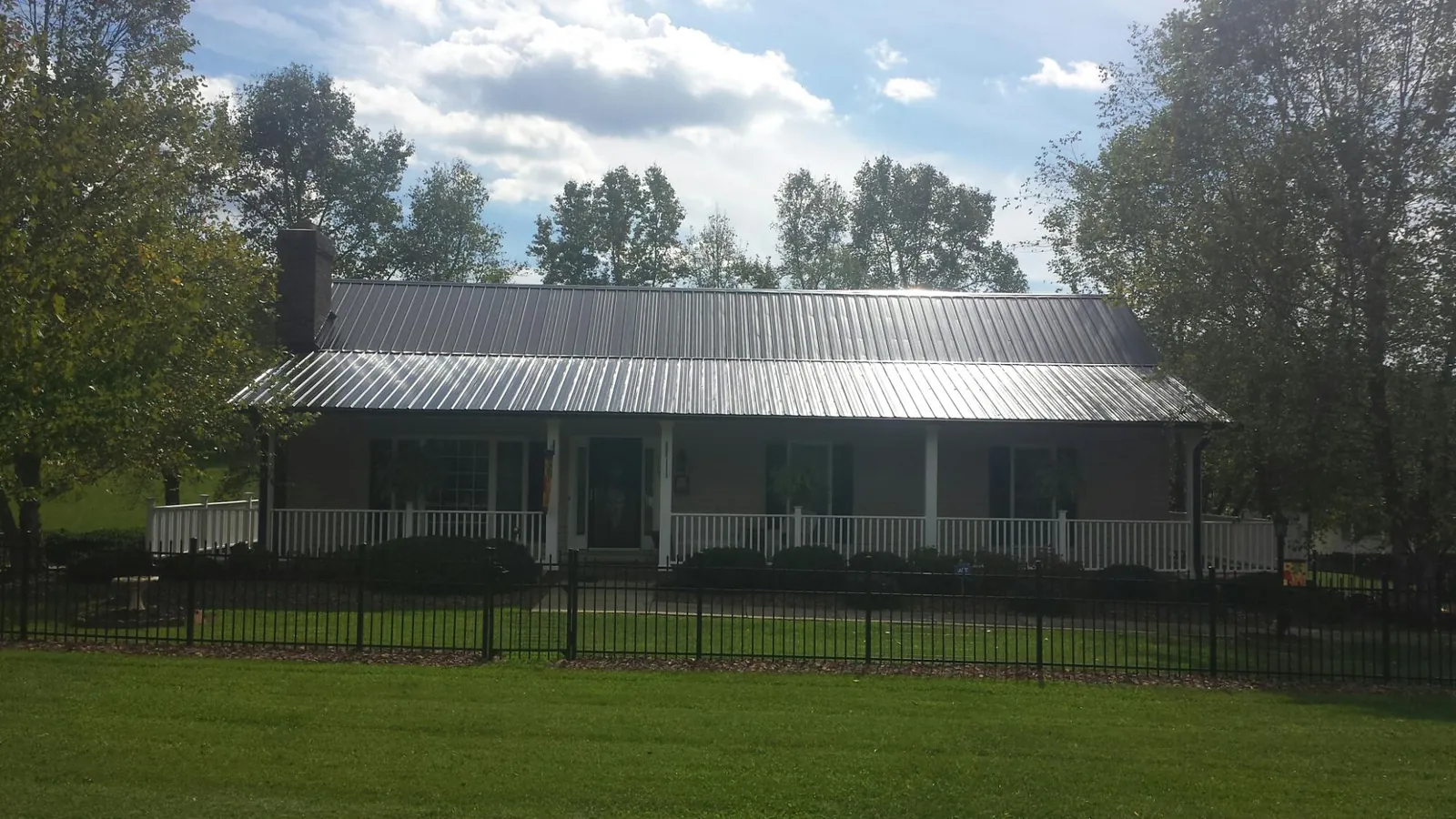 Gray metal roof on a brick ranch with a full width front porch — Gutter Guard Installation work by our crew in Saddle Brook