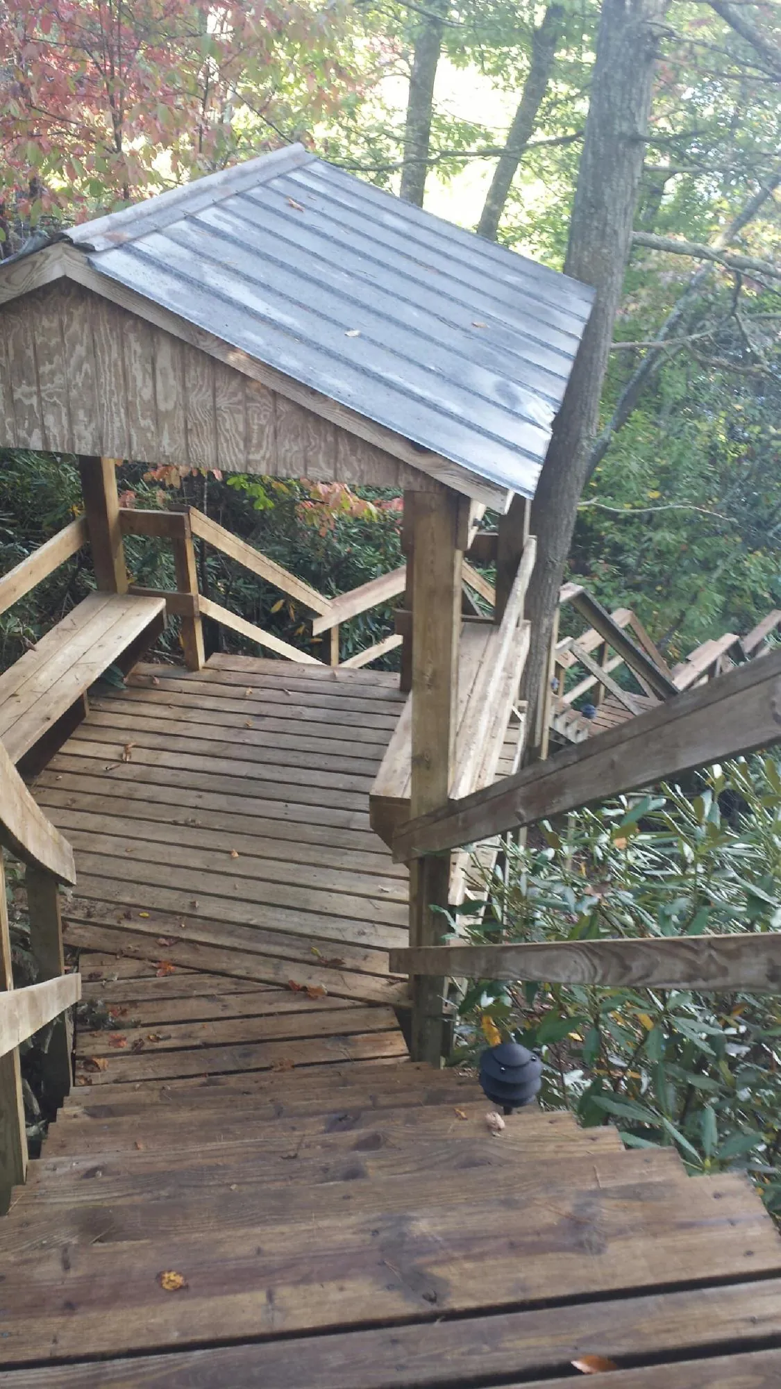 Metal roofed shelter over wooden steps on a wooded walkway — Skylight Repair & Installation work by our crew in Saddle Brook