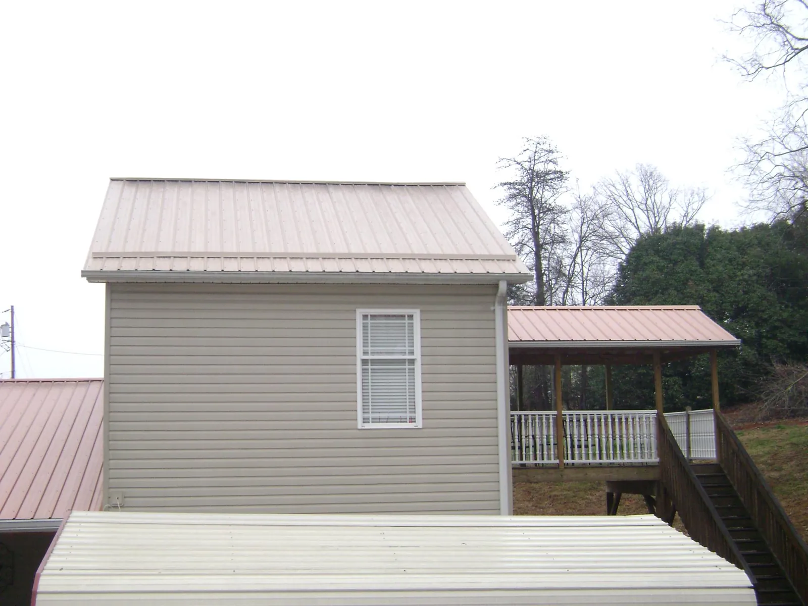 Tan metal roofs on a two story addition and attached porch, from a Roof Replacement job in Saddle Brook